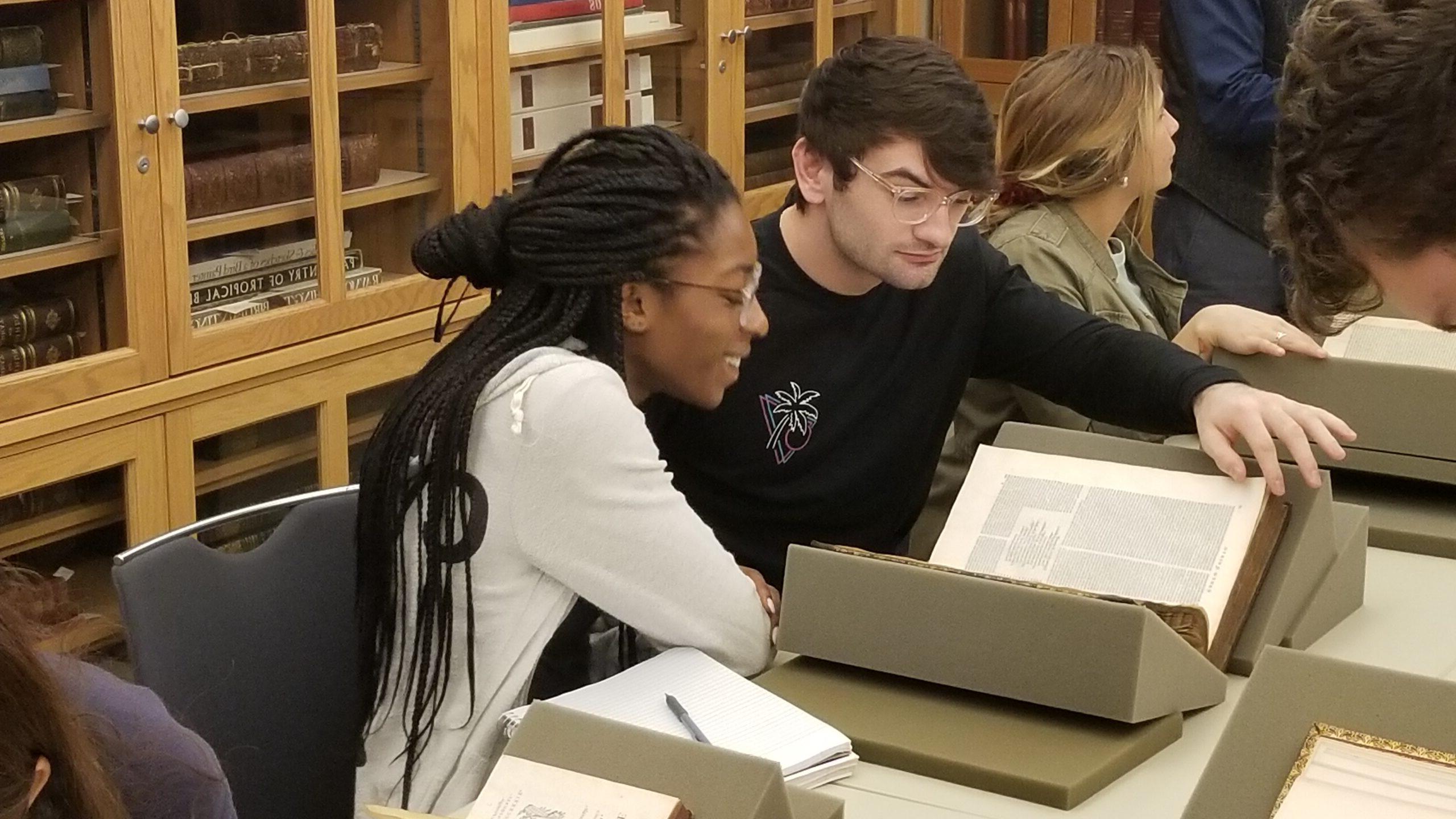 男学生和女学生在沃特金森图书馆的研讨室里看珍本图书